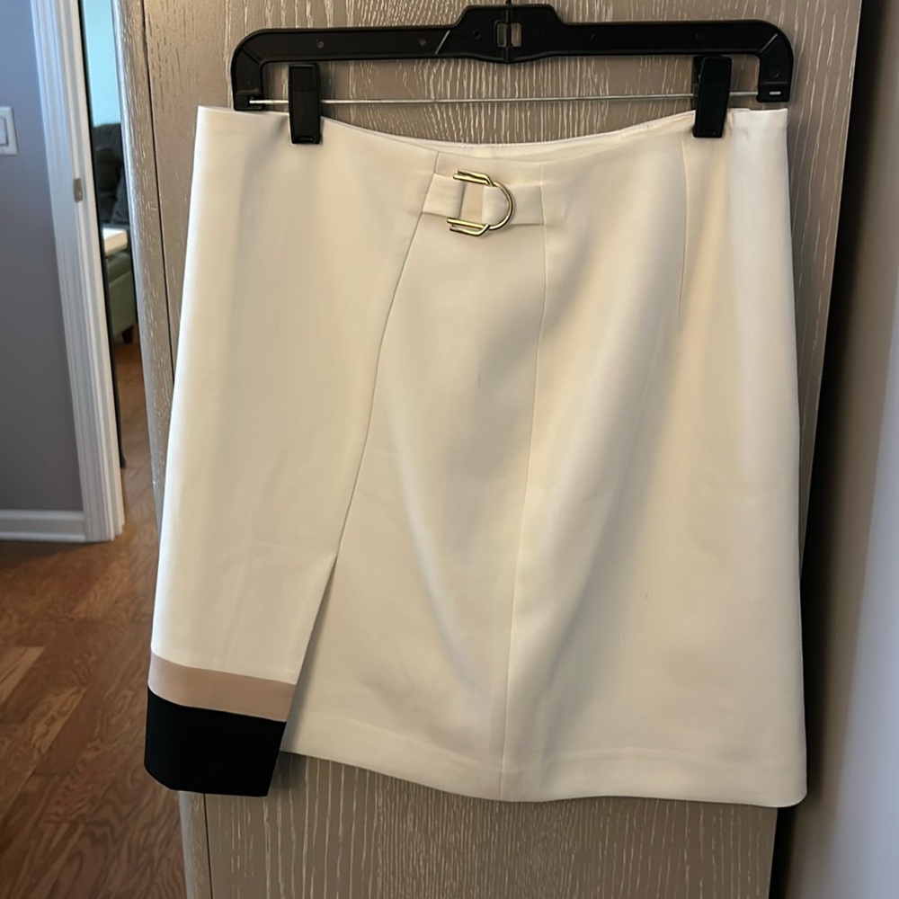 Cream color skirt with tan and black asymmetrical stripe at slit around the back